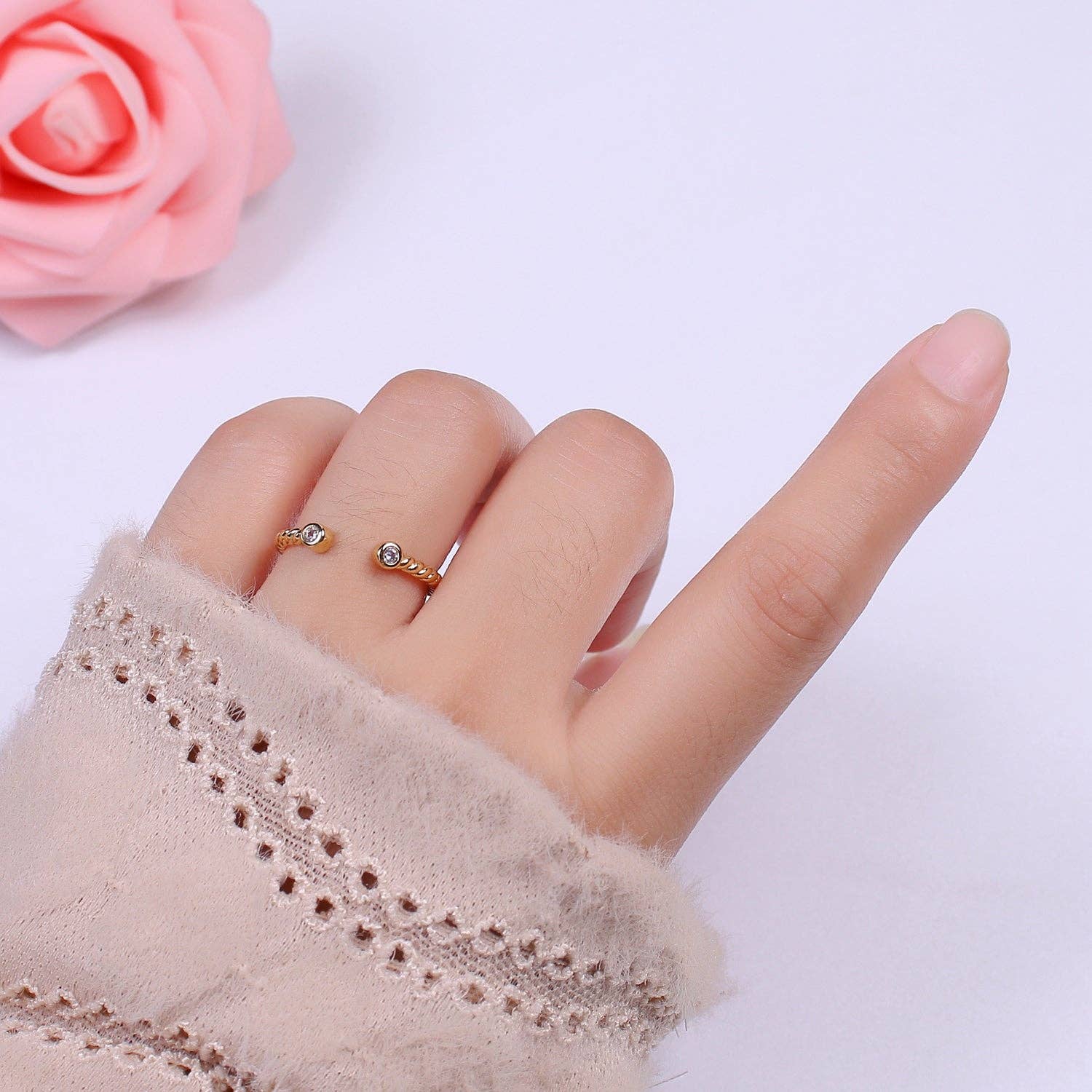 a hand with an open cuff  ring on it next to a rose
