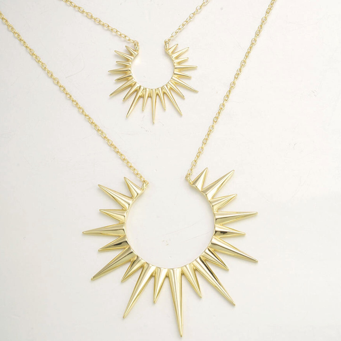 a pair of gold necklaces with spikes on them