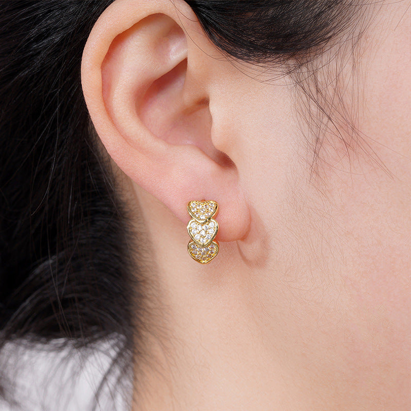 a close up of a person wearing a pair of heart earrings