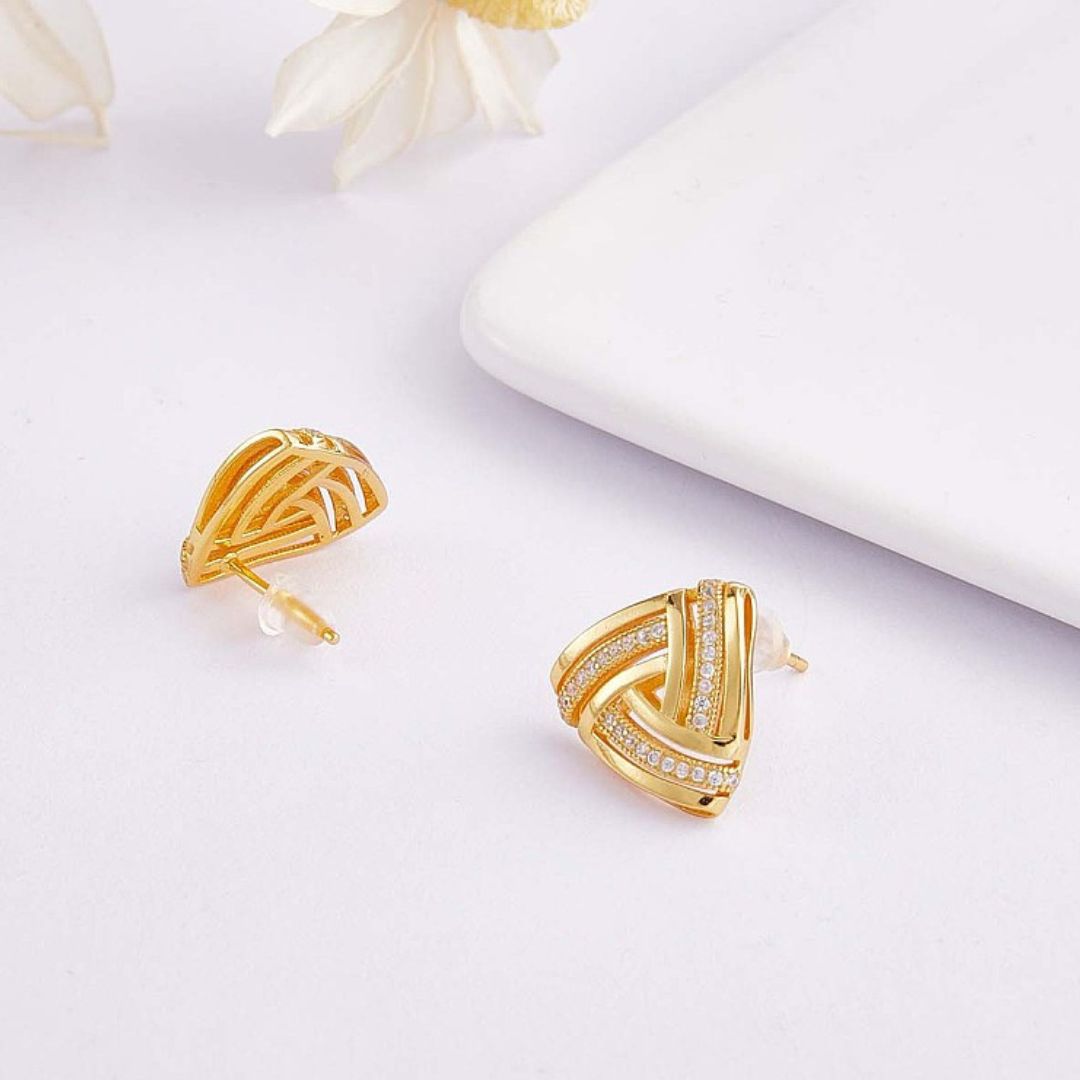 a pair of small gold earrings with clear stones on white background
