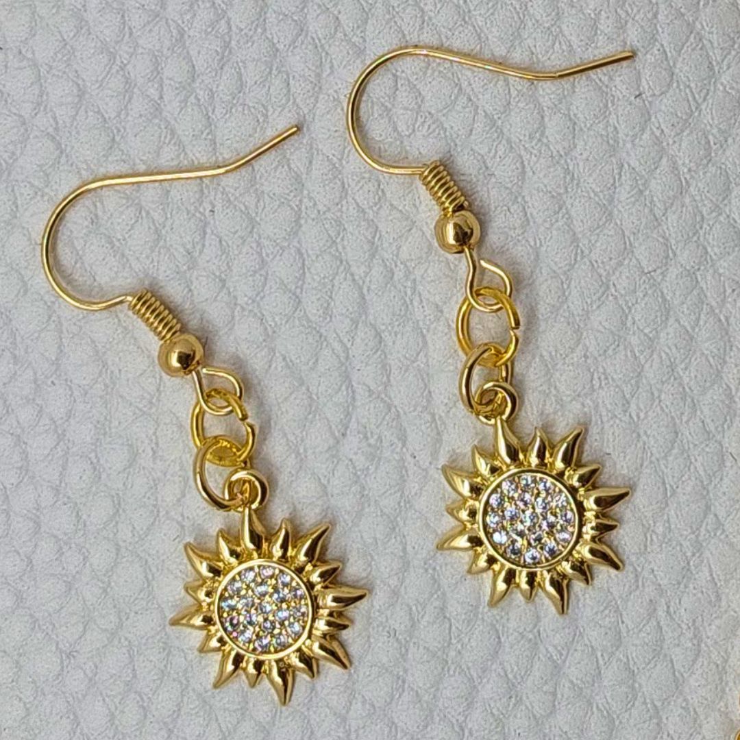 a pair of earrings with a sun design on them