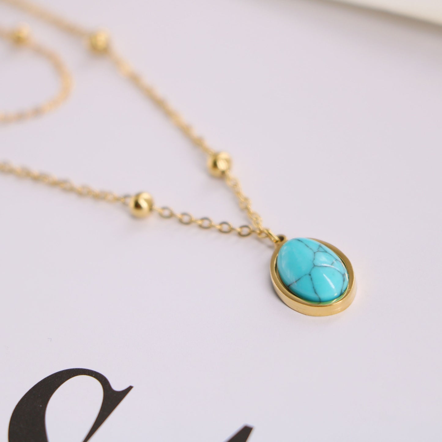a gold necklace with a turquoise stone on it